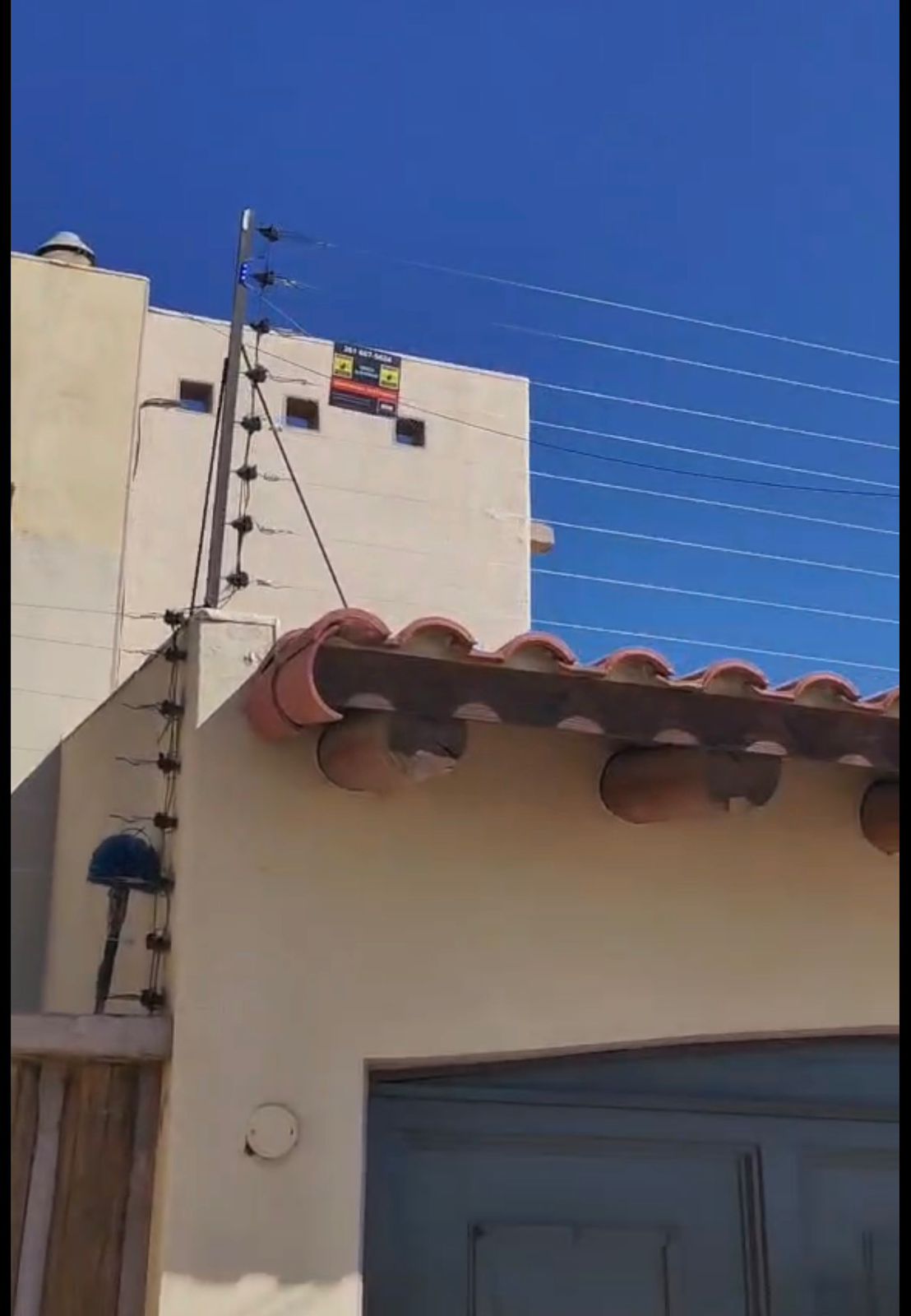 Energizador de cerco eléctrico instalado en la esquina de una vivienda